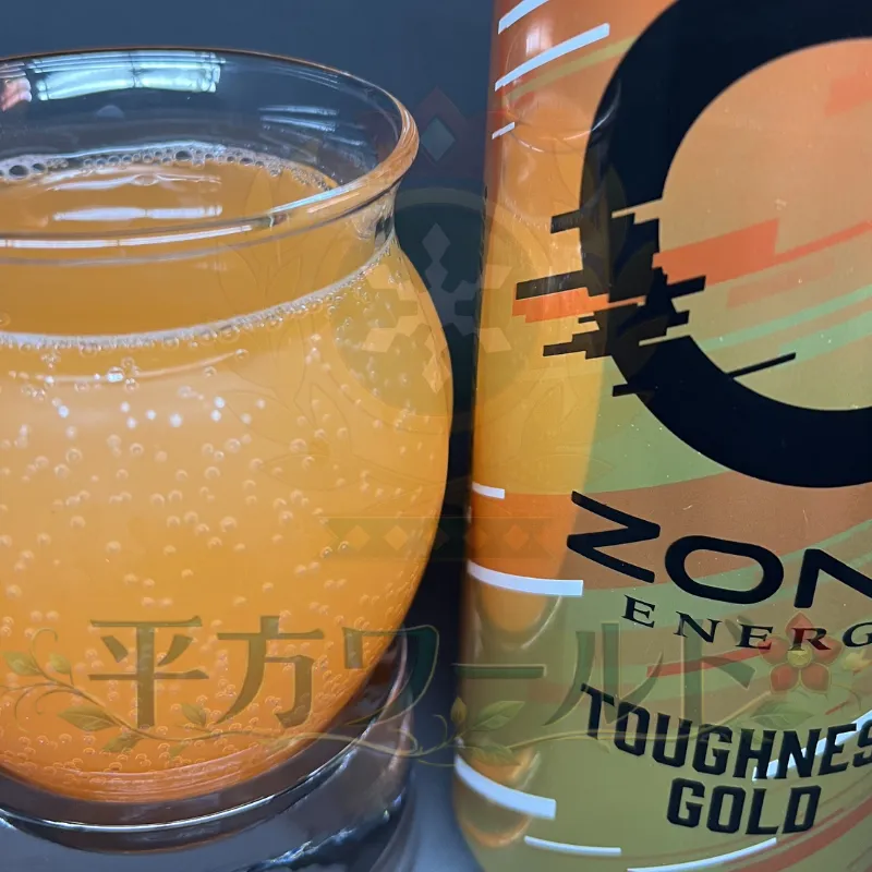 alt="ZONe ENERGY TOUGHNESS GOLDの缶と、グラスに注いだオレンジ色の中身を写した写真"