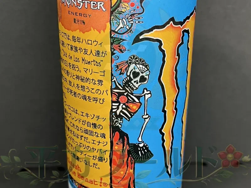 モンスター マンゴーロコの缶側面に描かれた、花飾りと衣装を身につけた骸骨の人物イラスト