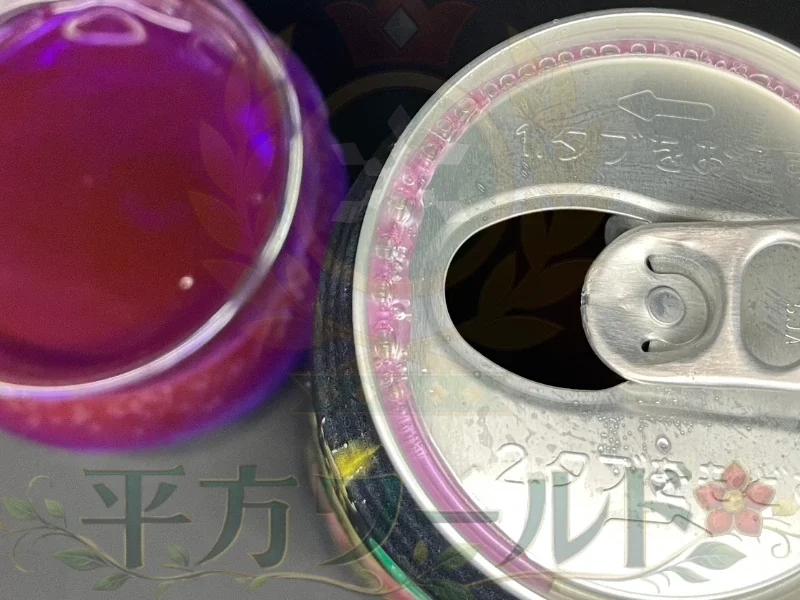 ゴジラエナジーⅤの飲み口とグラスを上から撮影。赤紫色の液体と缶の縁に映る紫色の光
