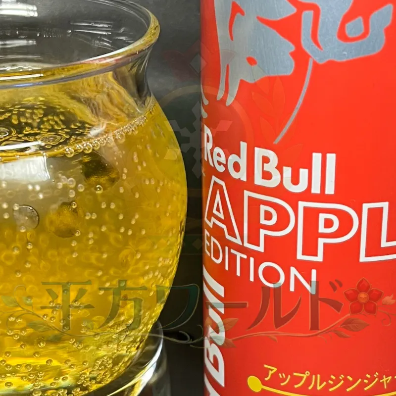 レッドブル アップルエディションの赤い缶と、グラスに注いだ黄金色のエナジードリンク